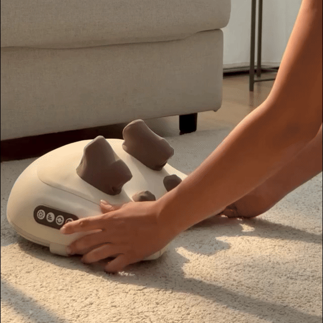 Person using a foot massager on a carpeted floor with a couch in the background